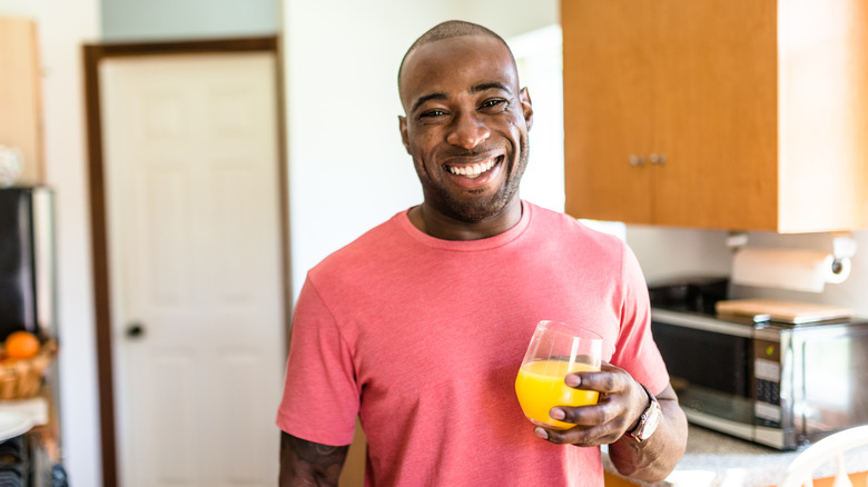 man drinking glass of orange juice
