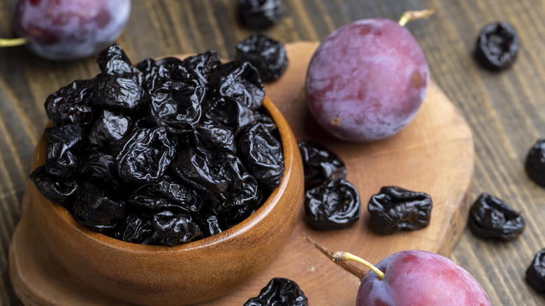 Bowl of prunes on wooden surface