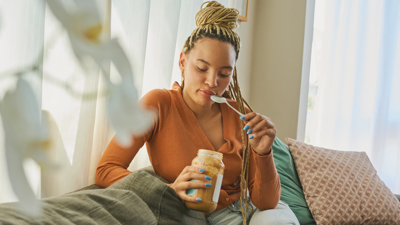 Woman eating spoonful of peanut butter