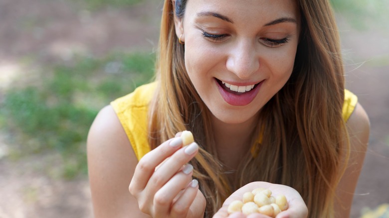 Smiling woman holding handful of macadamia nuts