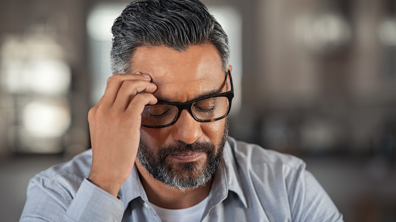 Stressed man holding hand to his head