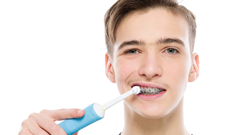 Boy with braces brushing teeth