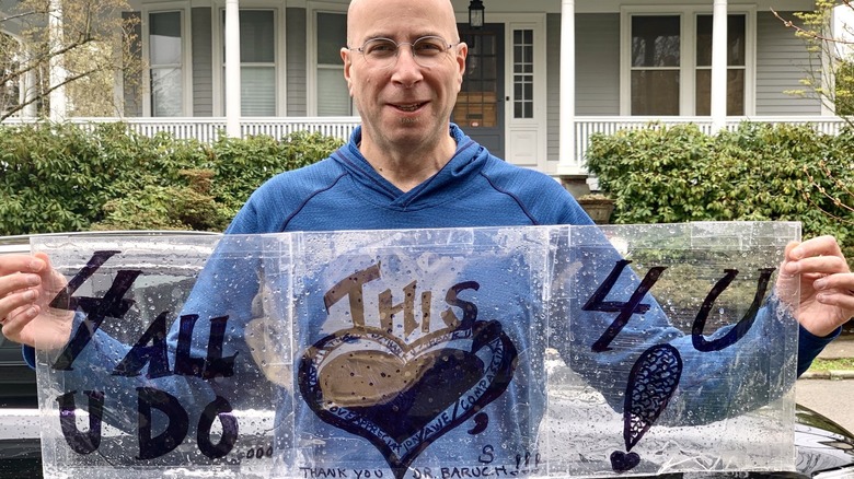 Dr. Jay Baruch holding a sign made to thank him for his work in the ER