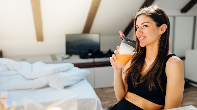 A woman drinks an energy supplement before working out