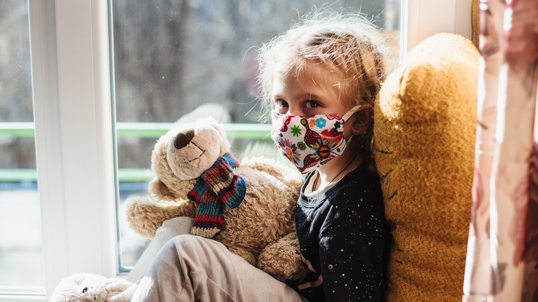 A masked child holding a bear
