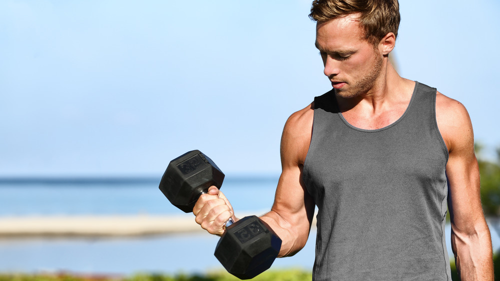 man outdoors holding free weight