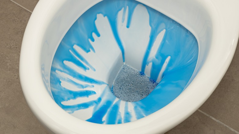 blue water spilling into toilet bowl