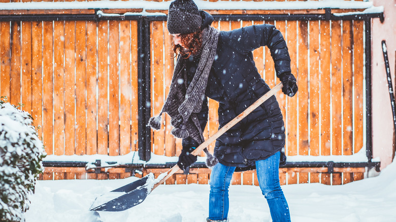 woman in winter gear shoveling snow