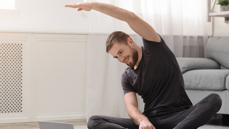 man stretching out on yoga mat at home