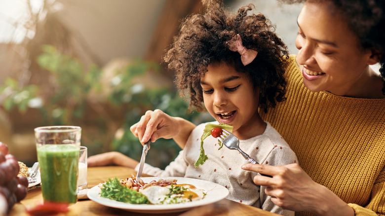 Mother serves daughter salad