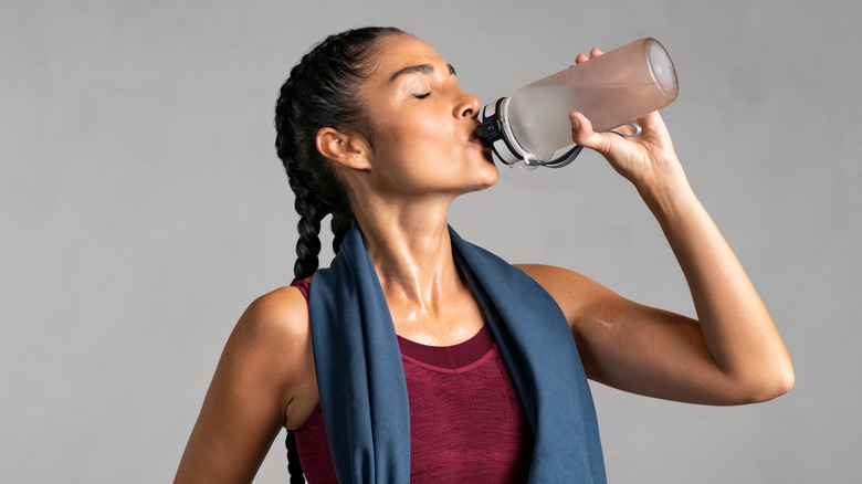 woman drinking water after workout