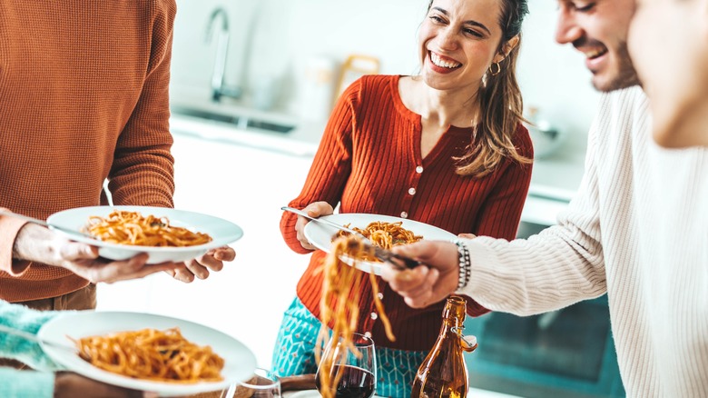 Friends eating pasta together at home