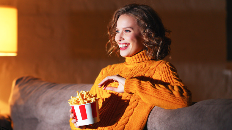 Woman eating fries on her couch