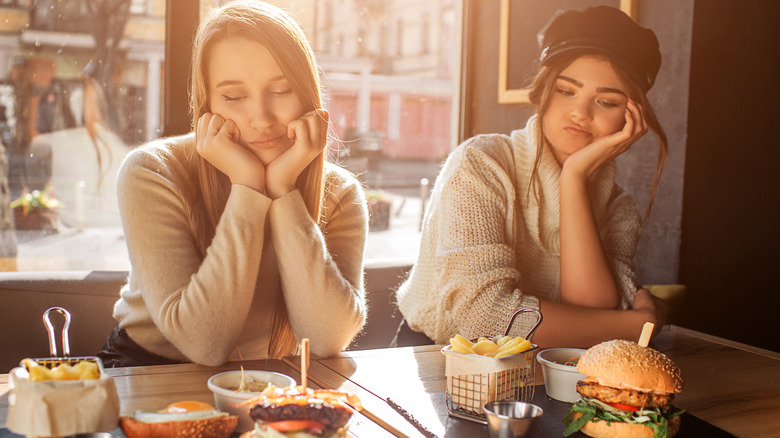 Two young women frowning at their food