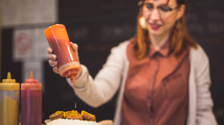 Woman squeezing ketchup onto food