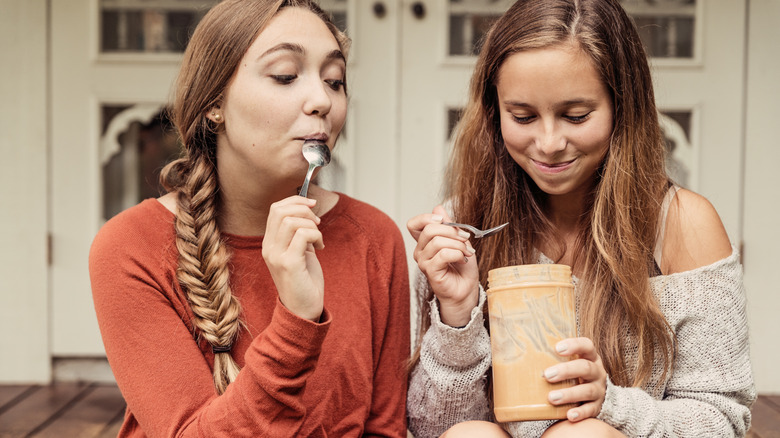 Happy girls eating peanut butter from the jar