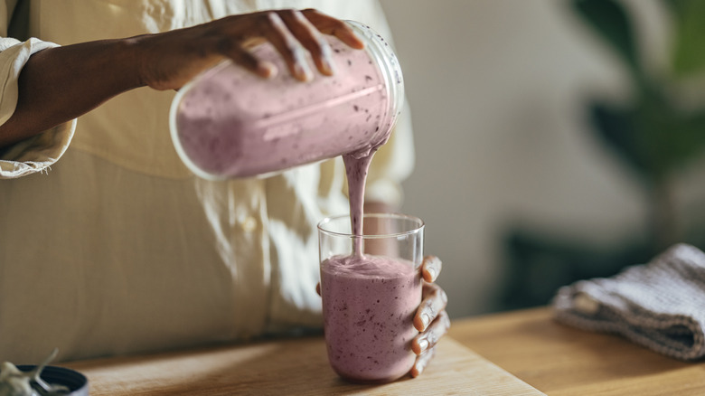 woman pouring a smoothie into a glass