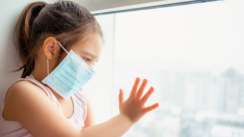 masked child looking out window