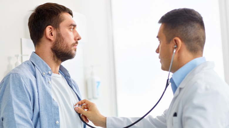 doctor checking man's heart