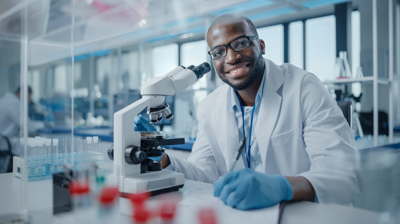 a scientist smiling with a microscope