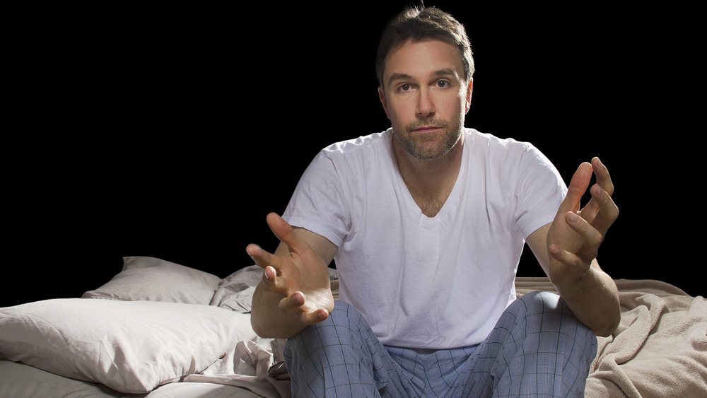 man sitting on bed's edge at night