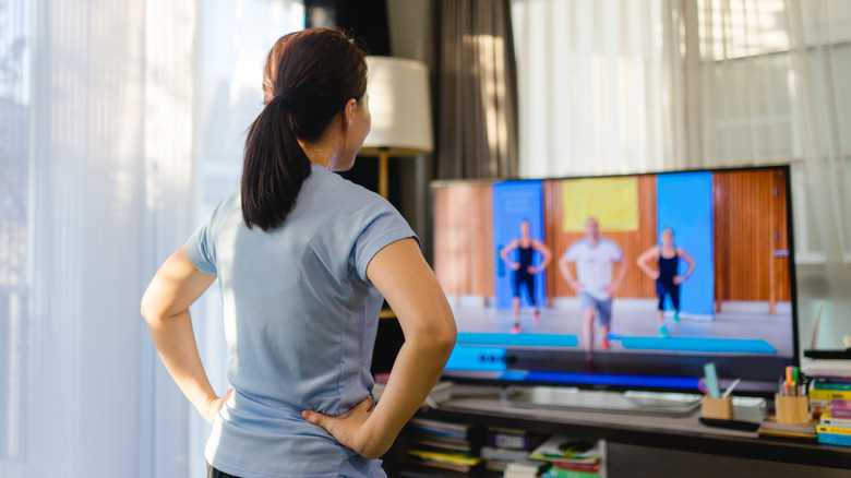 woman doing exercise routine in front of television