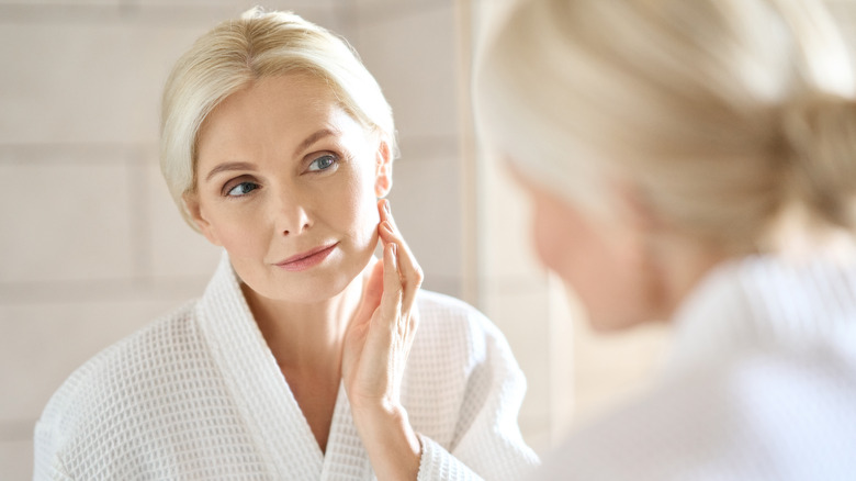 beautiful middle-aged woman looking in mirror