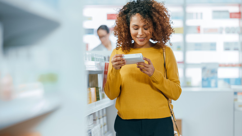 woman reading supplement bottle at drugstore