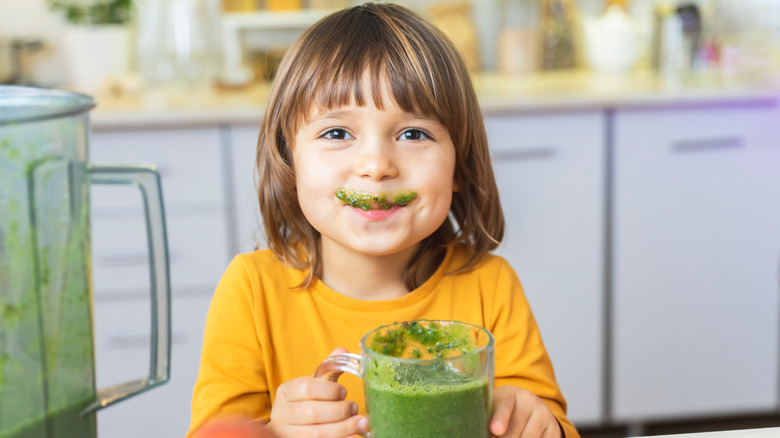 Young child drinking green smoothie