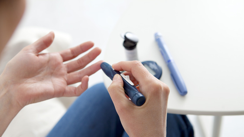 woman testing finger with glucometer