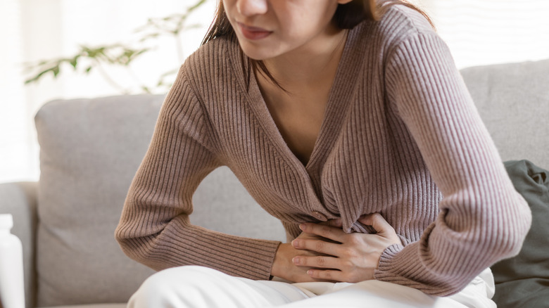 Woman hunched in pain clutching abdomen