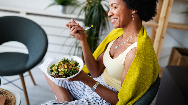 Black woman eating salad and smiling