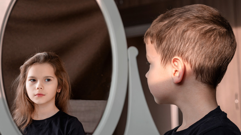 Young boy seeing girl in mirror