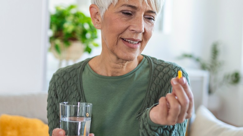 Older woman holding pill and glass 