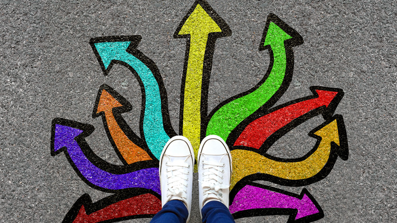 Woman's feet standing on arrows going in different directions