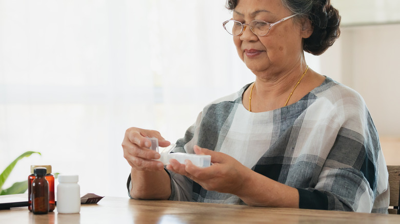 Older Asian woman sorting pills