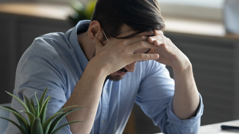 Depressed man with head in hands