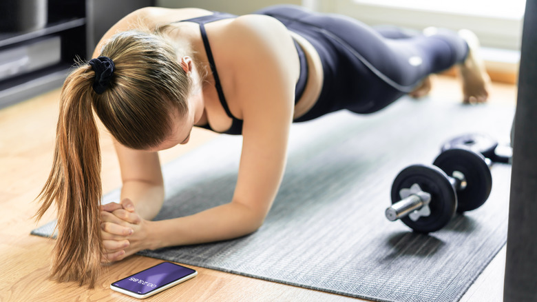 Woman in plank pose viewing smartphone