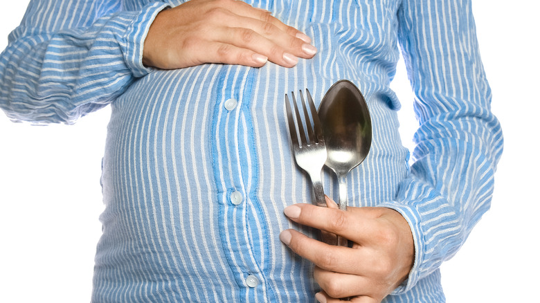 pregnant woman in blue shirt with utensils
