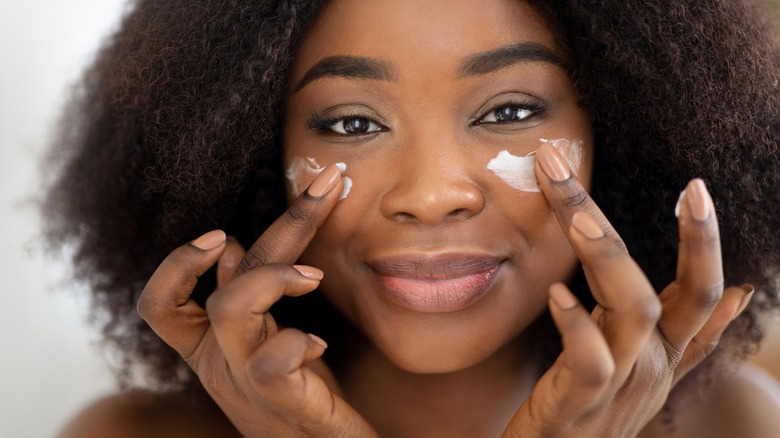 Woman applying moisturizer to her face