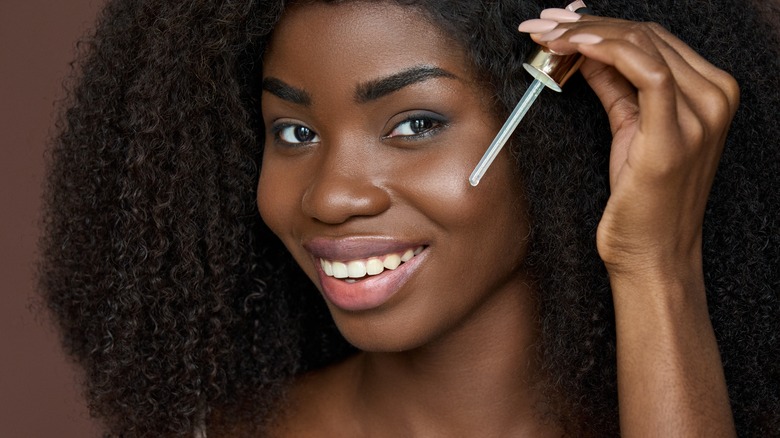 Woman applying a serum to her face