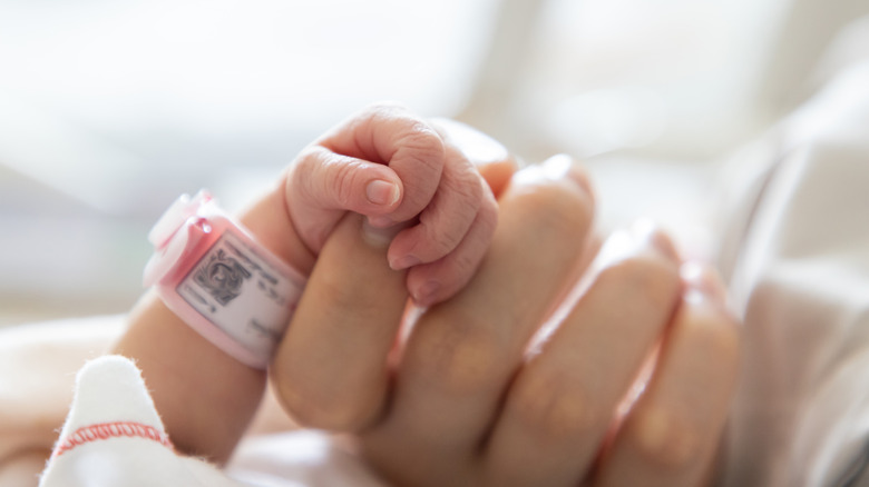 Baby holding mother's finger