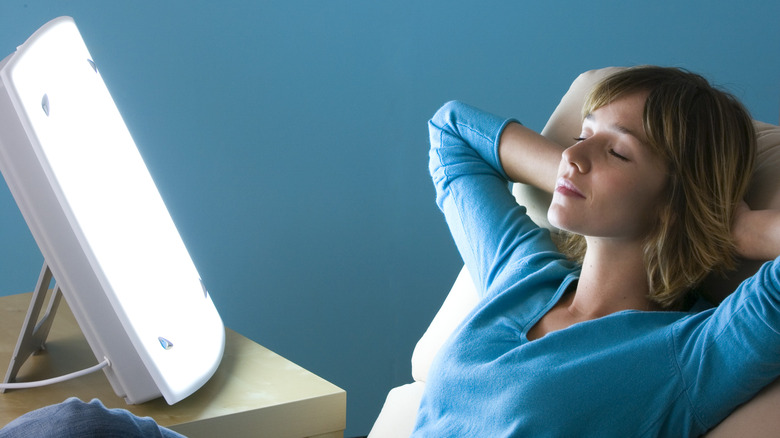 Woman lounging in a chair next to a light box 