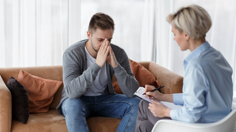 Man sitting on a couch talking to a therapist 