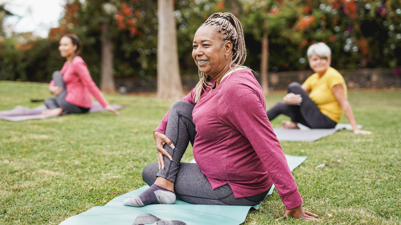 Black woman doing yoga outdoors with two other people