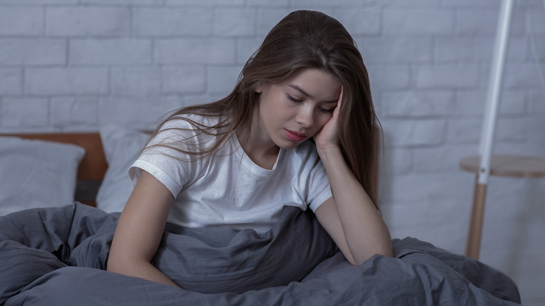 Woman sitting in bed looking sad