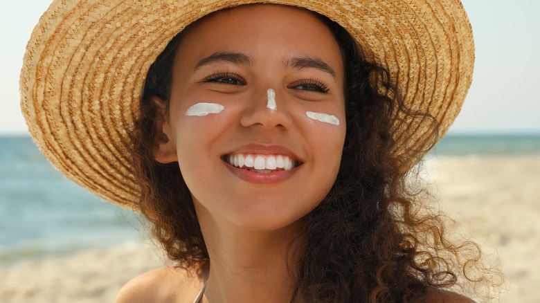 Woman in hat wearing sunscreen
