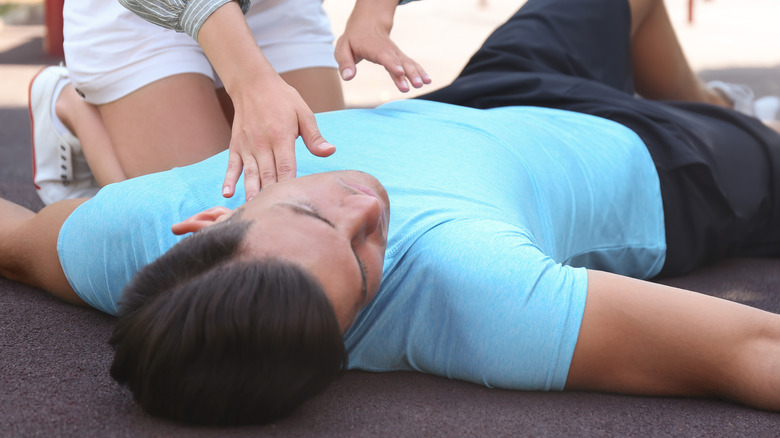 Woman kneeling and helping fainted man