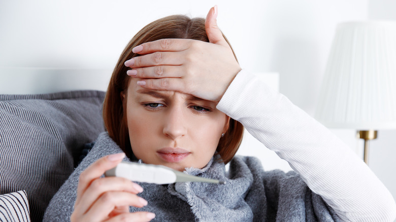 Woman holding head and checking temperature