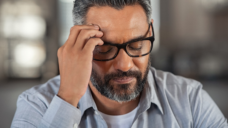 Man in glasses holding head